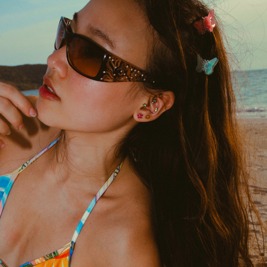 Woman in a colorful bikini, earrings, and sunglasses on a beach