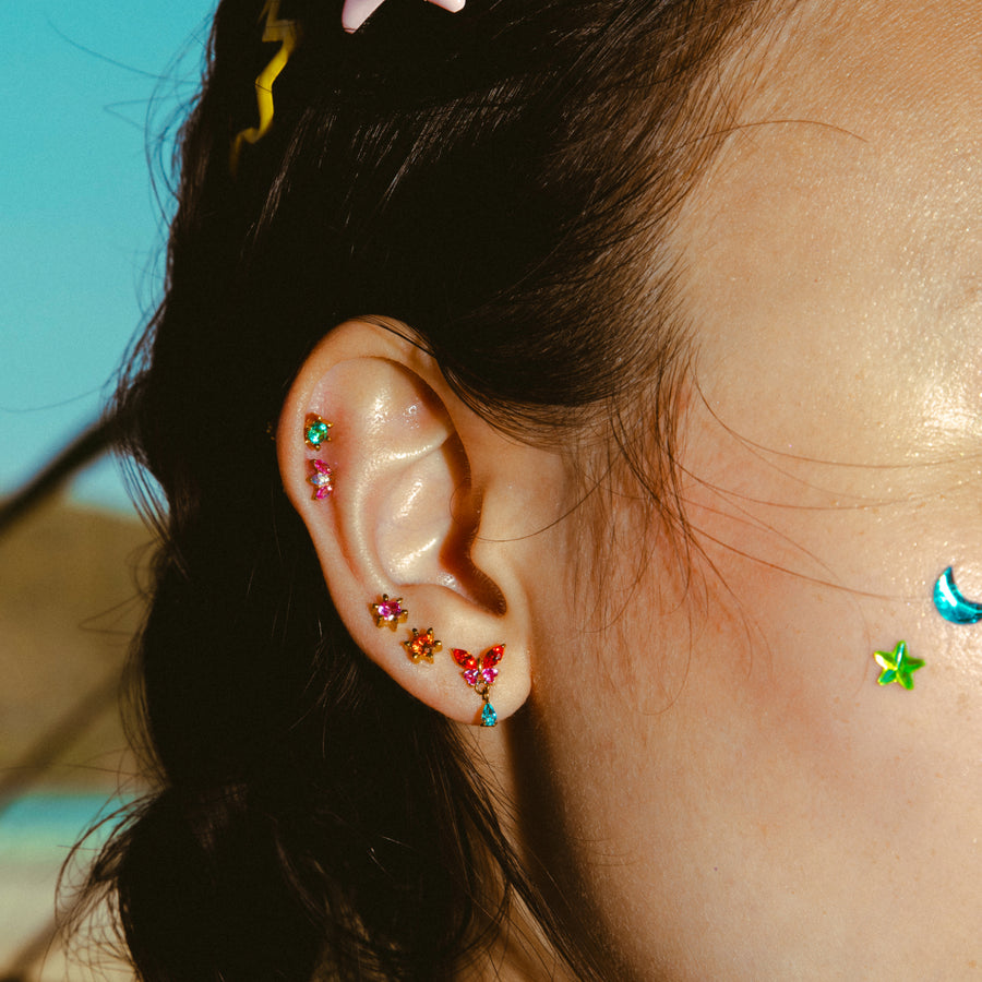 Close-up of an ear with colorful earrings against a blurred natural background