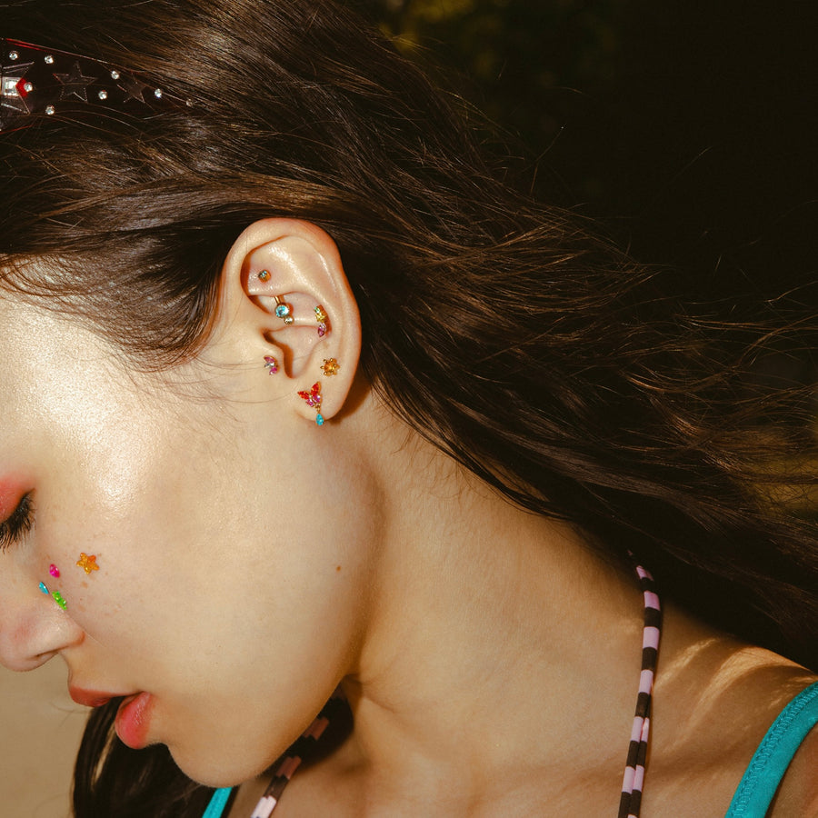 Close-up of a person's ear with colorful earrings against a blurred background