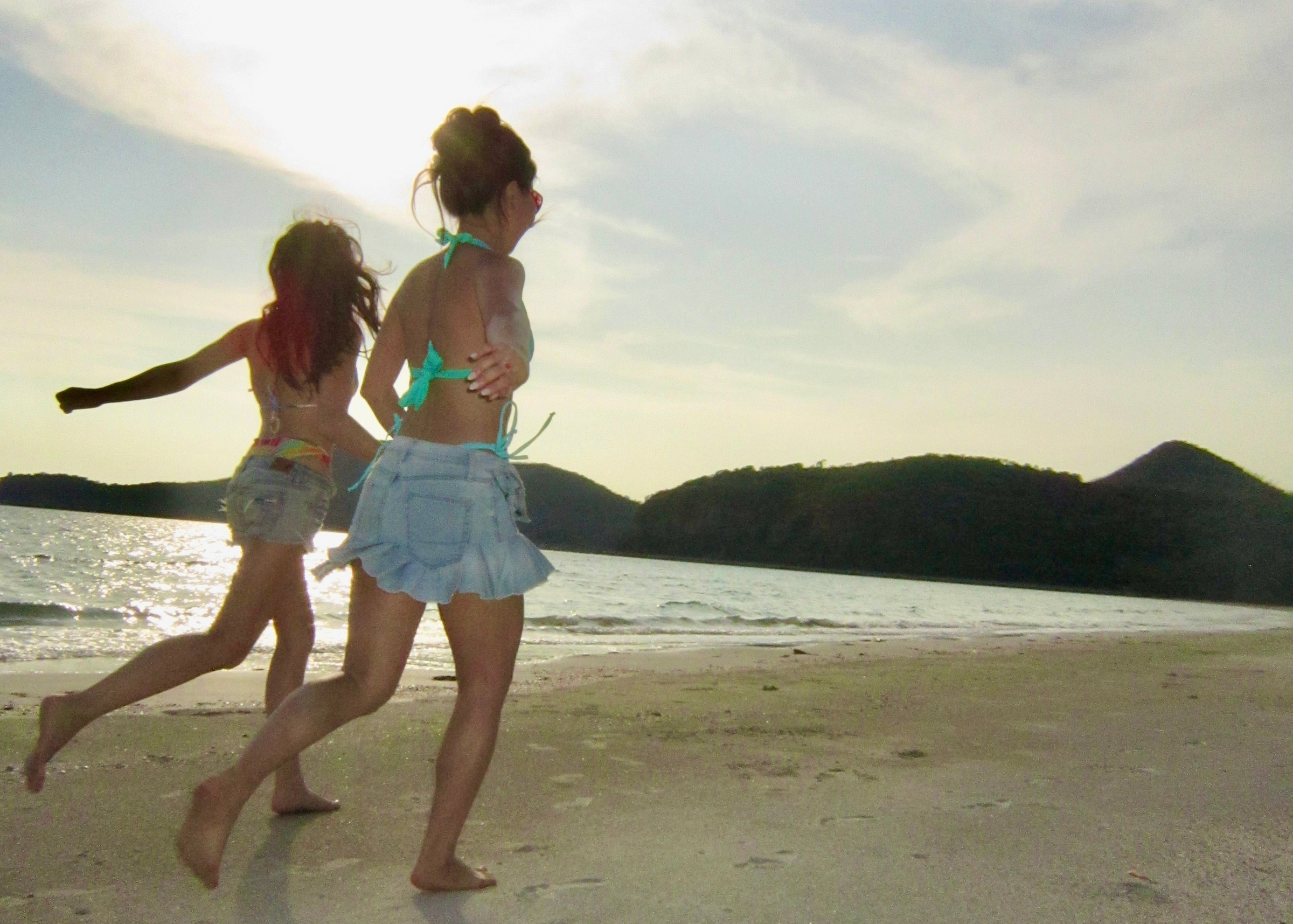 two women running on beach with mountains in the background